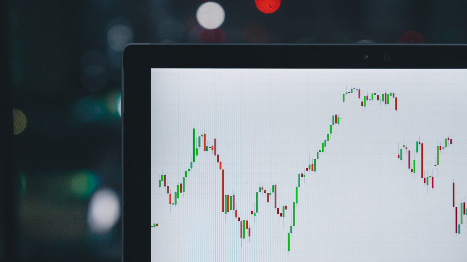 A laptop screen showing a line chart of financial data on a wooden desk.