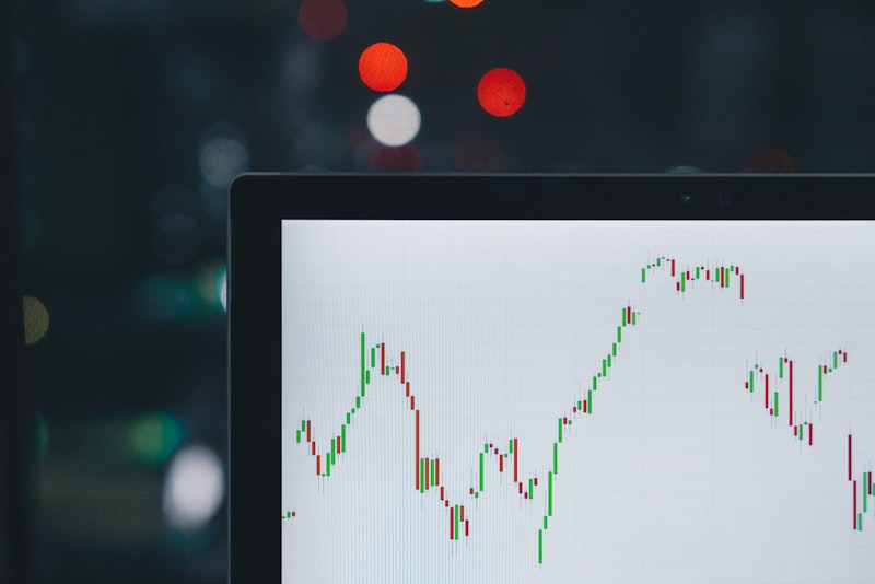A laptop screen showing a line chart of financial data on a wooden desk.
