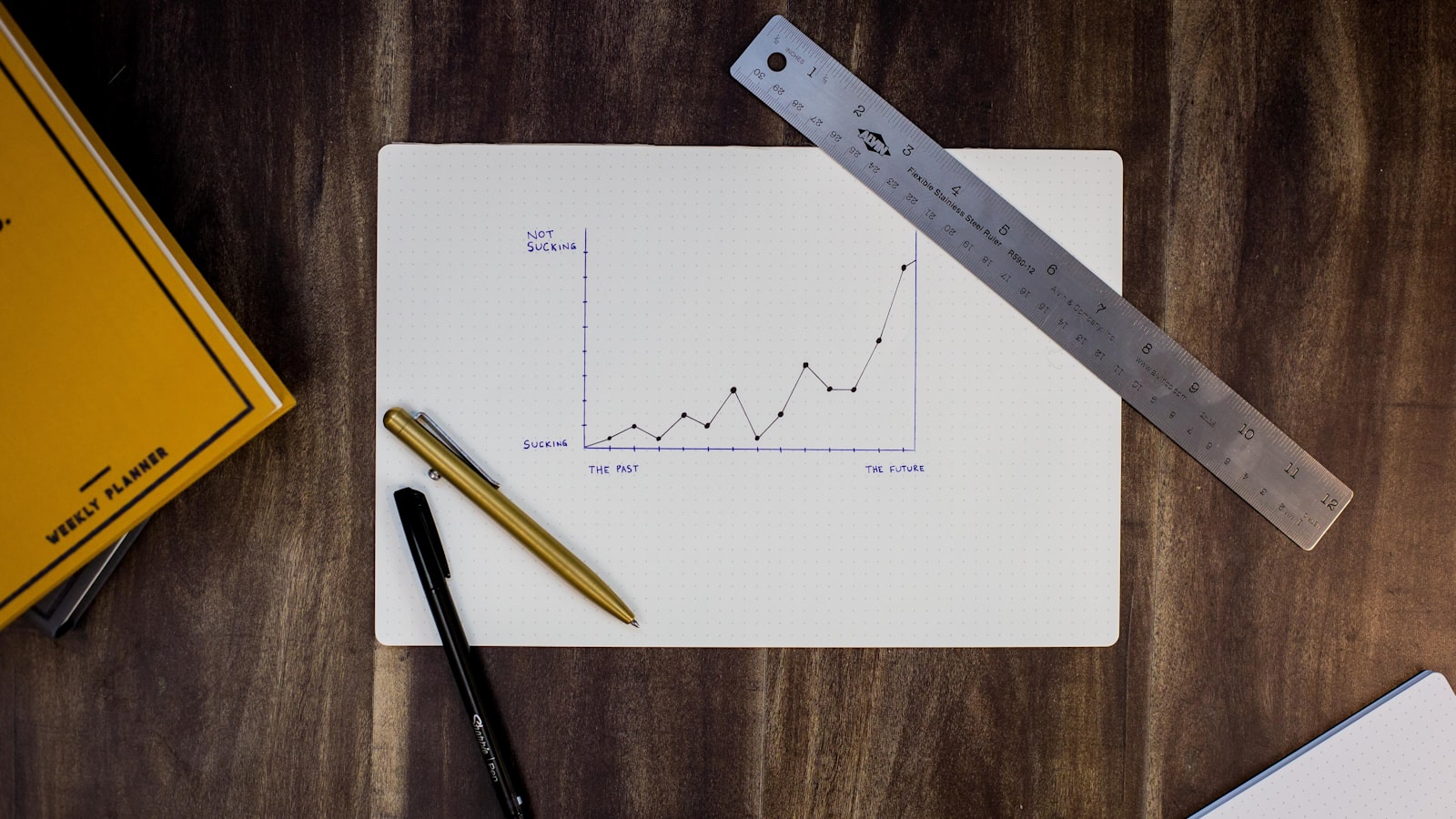 A calendar and a pen on a plain wooden desk